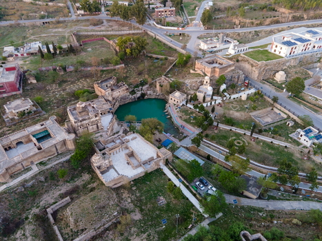 Aerial view of the historic Katas Raj Temple Complex featuring ancient stone structures and a sacred turquoise pond surrounded by lush greenery and pathways in Katas Punjab Pakistan. Aerial view of the historic Katas Raj Temple Complex featuring ancient stone structures and a sacred turquoise pond surrounded by lush greenery and pathways in Katas Punjab Pakistan.