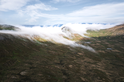 Aerial view of Hornstrandir Nature Reserve with low clouds rolling over rugged mountain ridges and tundra landscape in Isafjordur Isafjardabaer Iceland. Aerial view of Hornstrandir Nature Reserve with low clouds rolling over rugged mountain ridges and tundra landscape in Isafjordur Isafjardabaer Iceland.