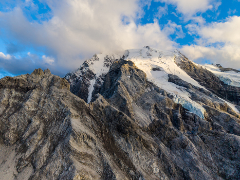 Aerial view of Ortler Mountain with its rugged rocky peaks snow covered glaciers and dramatic clouds under a blue sky in Stilfs Trentino Alto Adige Italy. Aerial view of Ortler Mountain with its rugged rocky peaks snow covered glaciers and dramatic clouds under a blue sky in Stilfs Trentino Alto Adige Italy.
