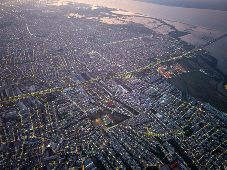 Aerial view of the old town at dusk with illuminated streets and buildings stretching towards the coastline Surabaya East Java Indonesia.