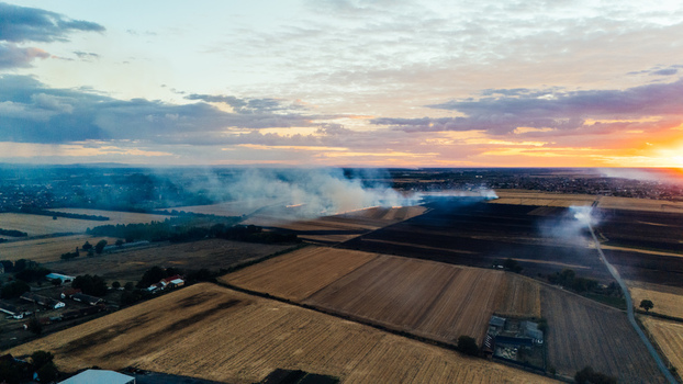 Aerial view of smoke rising from a fire in agricultural fields during sunset near Sremska Mitrovica Vojvodina Serbia. Aerial view of smoke rising from a fire in agricultural fields during sunset near Sremska Mitrovica Vojvodina Serbia.
