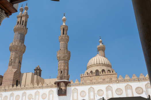 View of Al Azhar Mosque with its ornate stone minarets and a large dome under a clear blue sky in Cairo Egypt. View of Al Azhar Mosque with its ornate stone minarets and a large dome under a clear blue sky in Cairo Egypt.