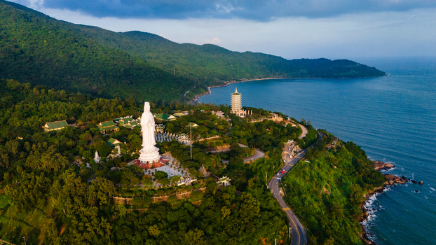 Aerial view of the giant Lady Buddha statue at Linh Ung Pagoda surrounded by lush green mountains and the blue coastline of Da Nang Vietnam. Aerial view of the giant Lady Buddha statue at Linh Ung Pagoda surrounded by lush green mountains and the blue coastline of Da Nang Vietnam.