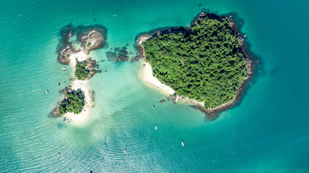 Aerial view of Ilha de Cataguas featuring lush green vegetation white sandy beaches and turquoise waters surrounded by small boats in the bay Angra dos Reis Rio de Janeiro Brazil.