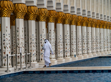 View of ornate white marble columns with gold leaf capitals and floral mosaics reflecting in a pool at the grand mosque in Dubai Dubai United Arab Emirates. View of ornate white marble columns with gold leaf capitals and floral mosaics reflecting in a pool at the grand mosque in Dubai Dubai United Arab Emirates.