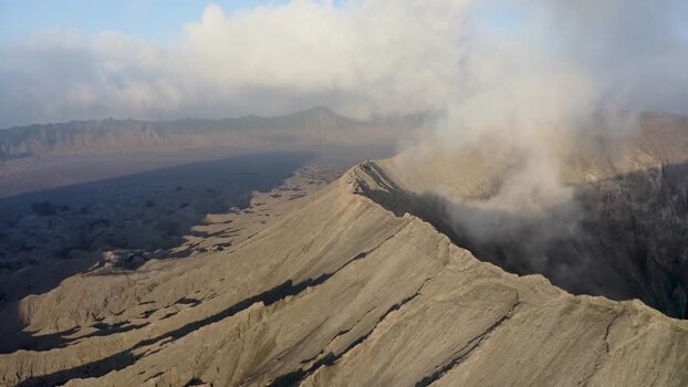 Aerial view of Mount Bromo crater with smoke rising in Indonesia. Aerial view of Mount Bromo crater with smoke rising in Indonesia.