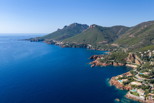 Aerial view of Le Trayas coastline featuring red rock cliffs Mediterranean Sea lush green hills and coastal villas in Saint Raphael Provence Alpes Cote d Azur France. Aerial view of Le Trayas coastline featuring red rock cliffs Mediterranean Sea lush green hills and coastal villas in Saint Raphael Provence Alpes Cote d Azur France.