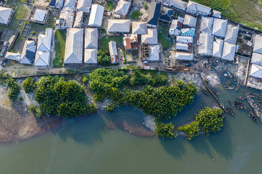 Port Harcourt Rivers Nigeria 03 July 2026 Aerial view of a coastal settlement with metal roofed houses dense shoreline vegetation and small wooden boats moored in the water. Port Harcourt Rivers Nigeria 03 July 2026 Aerial view of a coastal settlement with metal roofed houses dense shoreline vegetation and small wooden boats moored in the water.