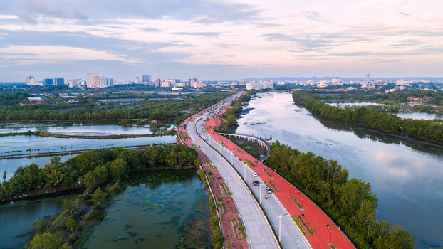 Iloilo City Philippines 18 July 2026 Aerial view of Iloilo Sunset Boulevard with its red path lush mangroves and fish ponds with the city skyline in the background.