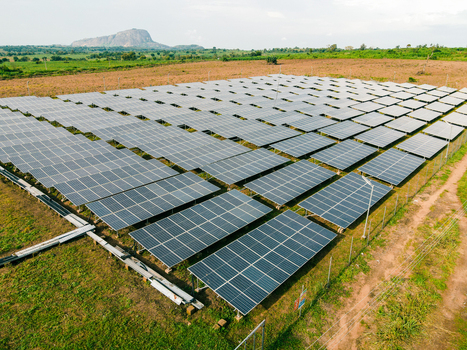 Aerial view of a large solar farm with rows of photovoltaic panels installed in a rural landscape with a distant hill in Ogun State Nigeria.