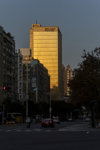 View of the Golden Tower skyscraper reflecting warm sunset light over a city street with traffic Taipei City Taiwan. View of the Golden Tower skyscraper reflecting warm sunset light over a city street with traffic Taipei City Taiwan.