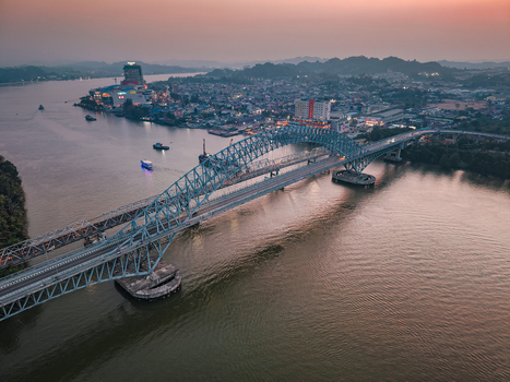 Aerial view of Jembatan Mahakam I spanning the Mahakam River at sunset with city buildings and boats in Kecamatan Samarinda Seberang Kalimantan Timur Indonesia. Aerial view of Jembatan Mahakam I spanning the Mahakam River at sunset with city buildings and boats in Kecamatan Samarinda Seberang Kalimantan Timur Indonesia.