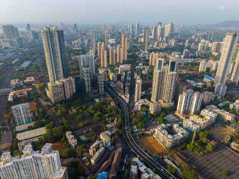 Aerial view of the dense urban skyline of Mumbai featuring high rise residential towers a major highway and green patches in Mumbai Maharashtra India. Aerial view of the dense urban skyline of Mumbai featuring high rise residential towers a major highway and green patches in Mumbai Maharashtra India.
