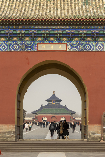 View of the Hall of Prayer for Good Harvests through a traditional red gate with people walking in the courtyard Beijing Beijing China. View of the Hall of Prayer for Good Harvests through a traditional red gate with people walking in the courtyard Beijing Beijing China.
