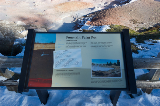 View of the Fountain Paint Pot information sign with geothermal mud pots in the background at Yellowstone National Park Wyoming United States. View of the Fountain Paint Pot information sign with geothermal mud pots in the background at Yellowstone National Park Wyoming United States.