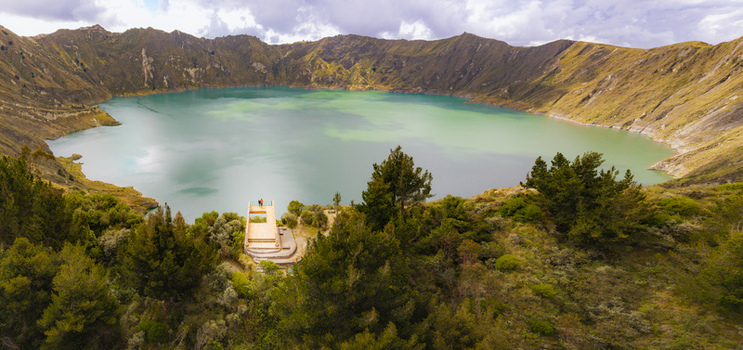 Aerial view of Quilotoa Lake with turquoise water inside a volcanic caldera surrounded by rugged slopes and lush vegetation in Quilotoa Cotopaxi Ecuador. Aerial view of Quilotoa Lake with turquoise water inside a volcanic caldera surrounded by rugged slopes and lush vegetation in Quilotoa Cotopaxi Ecuador.
