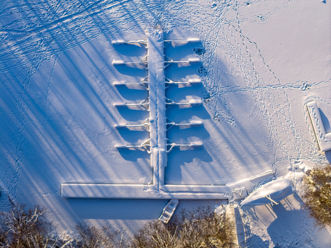 Aerial view of a snow covered boat dock on a frozen lake with long shadows and footprints in Trakai Vilnius County Lithuania. Aerial view of a snow covered boat dock on a frozen lake with long shadows and footprints in Trakai Vilnius County Lithuania.