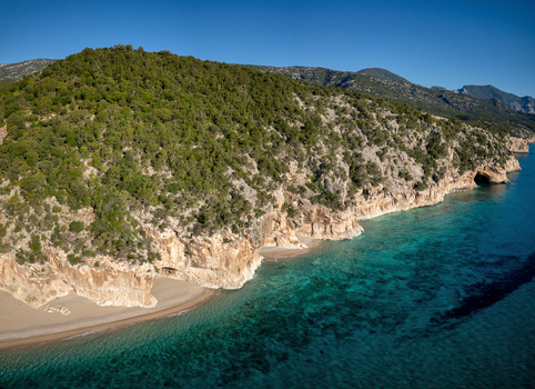 Aerial view of Cala Luna beach with turquoise waters limestone cliffs and lush Mediterranean vegetation Baunei Sardegna Italy. Aerial view of Cala Luna beach with turquoise waters limestone cliffs and lush Mediterranean vegetation Baunei Sardegna Italy.