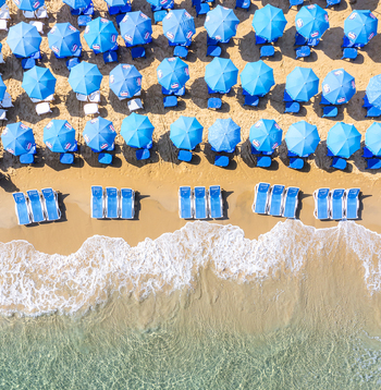 Aerial view of Bat Yam beach featuring rows of blue umbrellas and sun loungers on golden sand by the turquoise sea Bat Yam Center District Israel. Aerial view of Bat Yam beach featuring rows of blue umbrellas and sun loungers on golden sand by the turquoise sea Bat Yam Center District Israel.