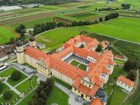 Aerial view of Stift Stams a historic Cistercian monastery with onion domed towers and red tiled roofs surrounded by lush green fields and agricultural land in Stams Tirol Austria. Aerial view of Stift Stams a historic Cistercian monastery with onion domed towers and red tiled roofs surrounded by lush green fields and agricultural land in Stams Tirol Austria.