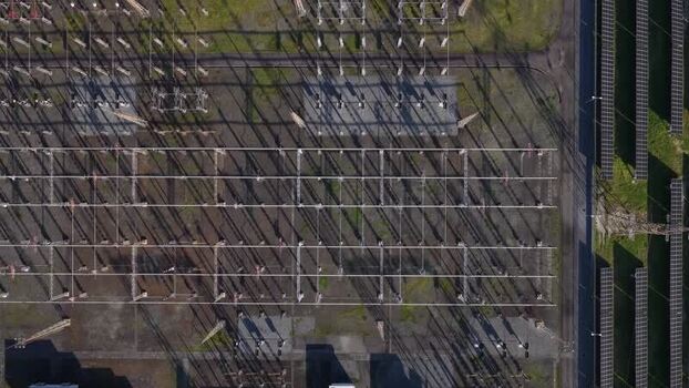 Aerial view of a symmetrical grid of electrical infrastructure casting long shadows