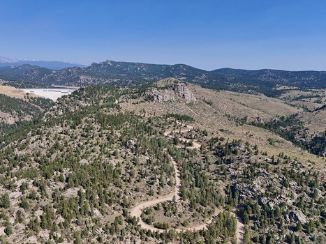 Aerial view of the winding dirt road at Crescent Meadows Trailhead surrounded by pine trees rocky terrain and rolling mountains in Golden Colorado United States. Aerial view of the winding dirt road at Crescent Meadows Trailhead surrounded by pine trees rocky terrain and rolling mountains in Golden Colorado United States.