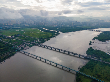 Aerial view of the Thane Creek bridge spanning the wide river with lush green wetlands urban skyline in the distance and cloudy sky in Thane Maharashtra India. Aerial view of the Thane Creek bridge spanning the wide river with lush green wetlands urban skyline in the distance and cloudy sky in Thane Maharashtra India.