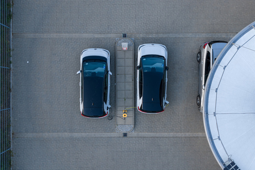 Aerial view of two white electric cars charging at the ENTEGA Charging Station on a paved parking lot in Darmstadt Hessen Germany. Aerial view of two white electric cars charging at the ENTEGA Charging Station on a paved parking lot in Darmstadt Hessen Germany.