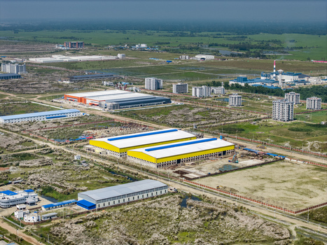 Aerial view of Mirsarai Economic Zone featuring industrial warehouses with yellow roofs surrounded by infrastructure and green fields in Minsarai Chittagong Division Bangladesh. Aerial view of Mirsarai Economic Zone featuring industrial warehouses with yellow roofs surrounded by infrastructure and green fields in Minsarai Chittagong Division Bangladesh.