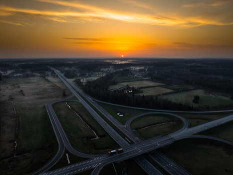 Aerial view of a highway interchange at sunset with golden light over the rural landscape and surrounding forests in Olaine parish Olaine Municipality Latvia. Aerial view of a highway interchange at sunset with golden light over the rural landscape and surrounding forests in Olaine parish Olaine Municipality Latvia.