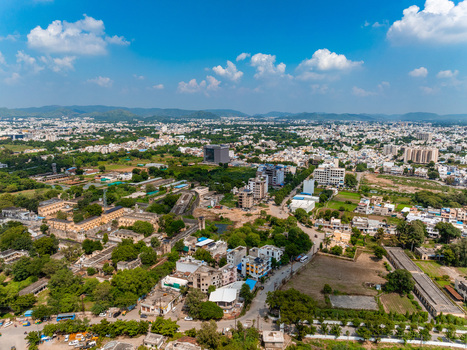 Aerial view of the urban landscape of Udaipur featuring residential and commercial buildings trees and roads stretching towards the distant hills in Udaipur Rajasthan India. Aerial view of the urban landscape of Udaipur featuring residential and commercial buildings trees and roads stretching towards the distant hills in Udaipur Rajasthan India.