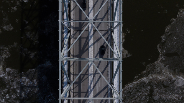 Aerial view of a steel truss bridge with cars driving over a partially frozen river with ice floes in Cincinnati Ohio United States. Aerial view of a steel truss bridge with cars driving over a partially frozen river with ice floes in Cincinnati Ohio United States.