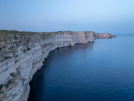 Aerial view of the rugged Sanap Cliffs plunging into the deep blue sea under the fading twilight Munxar Gozo Malta. Aerial view of the rugged Sanap Cliffs plunging into the deep blue sea under the fading twilight Munxar Gozo Malta.