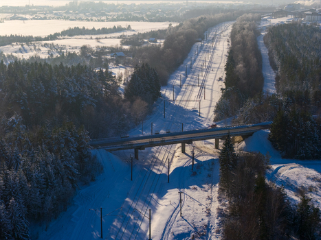 Aerial view of a railway line and a road bridge crossing through a snow covered coniferous forest in winter Lithuania. Aerial view of a railway line and a road bridge crossing through a snow covered coniferous forest in winter Lithuania.