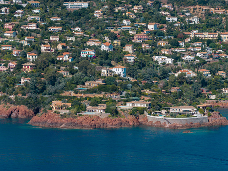 Aerial view of Le Trayas featuring luxury villas nestled among lush greenery and red rock cliffs overlooking the Mediterranean Sea Saint Raphael Provence Alpes Cote d Azur France. Aerial view of Le Trayas featuring luxury villas nestled among lush greenery and red rock cliffs overlooking the Mediterranean Sea Saint Raphael Provence Alpes Cote d Azur France.