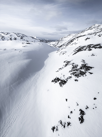 Aerial view of snowy mountain peaks and rocky slopes under an overcast winter sky in Kvaloya Troms Norway. Aerial view of snowy mountain peaks and rocky slopes under an overcast winter sky in Kvaloya Troms Norway.
