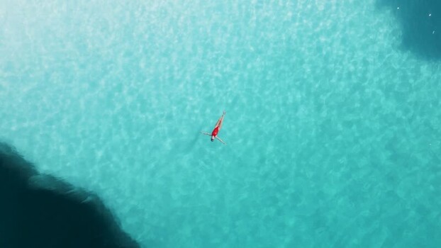 Aerial view of person floating in turquoise water Greenland. Aerial view of person floating in turquoise water Greenland.