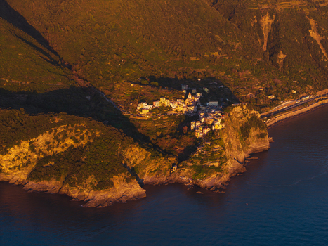 Aerial view of the historic village of Corniglia perched on a rocky cliff surrounded by lush green hills and terraced vineyards at sunset Corniglia Liguria Italy. Aerial view of the historic village of Corniglia perched on a rocky cliff surrounded by lush green hills and terraced vineyards at sunset Corniglia Liguria Italy.