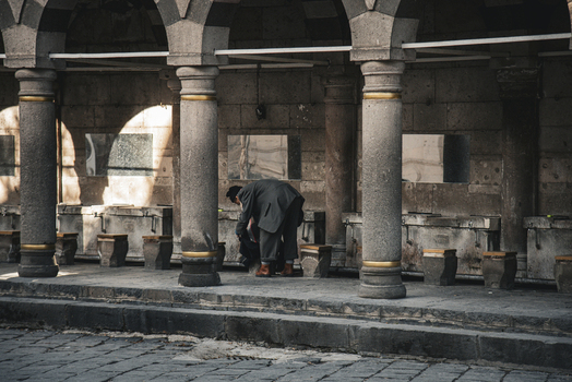View of a man in a suit at a traditional stone ablution station with arches and columns in Kayseri Kayseri Turkiye. View of a man in a suit at a traditional stone ablution station with arches and columns in Kayseri Kayseri Turkiye.