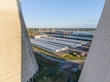 Aerial view of the Cargovil battery energy storage system framed by cooling towers featuring rows of energy storage containers near a canal in Vilvoorde Vlaanderen Belgium. Aerial view of the Cargovil battery energy storage system framed by cooling towers featuring rows of energy storage containers near a canal in Vilvoorde Vlaanderen Belgium.