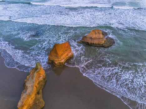 Aerial view of unique rock formations rising from the ocean surf along a sandy beach in Bali Bali Indonesia. Aerial view of unique rock formations rising from the ocean surf along a sandy beach in Bali Bali Indonesia.