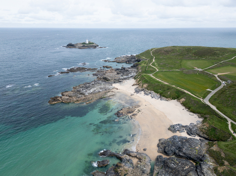 Aerial view of Godrevy Beach featuring its sandy shore turquoise waters and the iconic lighthouse on a rocky island in Gwithian England United Kingdom. Aerial view of Godrevy Beach featuring its sandy shore turquoise waters and the iconic lighthouse on a rocky island in Gwithian England United Kingdom.