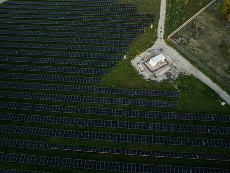 Aerial view of rows of solar panels in a photovoltaic power plant with a utility building and dirt path in Augusta Sicily Italy. Aerial view of rows of solar panels in a photovoltaic power plant with a utility building and dirt path in Augusta Sicily Italy.