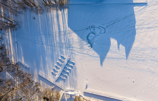 Aerial view of the long shadows of Trakai Island Castle cast over the snow covered frozen Lake Galve with a wooden pier and winter trees in Trakai Vilnius County Lithuania. Aerial view of the long shadows of Trakai Island Castle cast over the snow covered frozen Lake Galve with a wooden pier and winter trees in Trakai Vilnius County Lithuania.