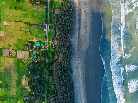 Aerial view of the long sandy coastline meeting the turquoise sea waves next to a lush green forest and agricultural fields in Cox s Bazar Chittagong Division Bangladesh. Aerial view of the long sandy coastline meeting the turquoise sea waves next to a lush green forest and agricultural fields in Cox s Bazar Chittagong Division Bangladesh.