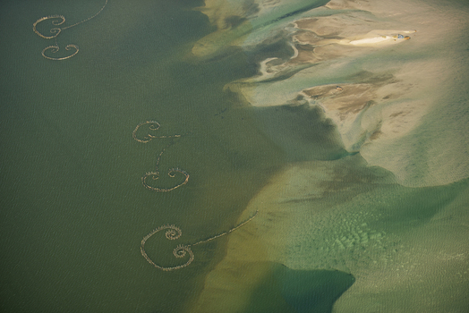 Aerial view of spiral shaped fish traps in shallow coastal waters with sandy shoals and clear turquoise sea in Rio de Janeiro Rio de Janeiro Brazil. Aerial view of spiral shaped fish traps in shallow coastal waters with sandy shoals and clear turquoise sea in Rio de Janeiro Rio de Janeiro Brazil.