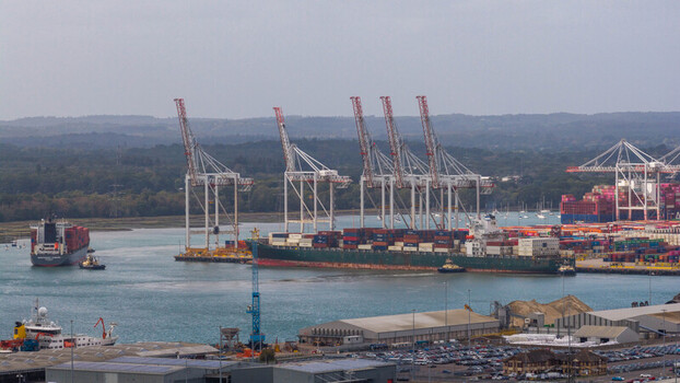 Aerial view of the busy Port of Southampton with large container ships towering gantry cranes and stacks of colorful cargo containers in Southampton England United Kingdom. Aerial view of the busy Port of Southampton with large container ships towering gantry cranes and stacks of colorful cargo containers in Southampton England United Kingdom.