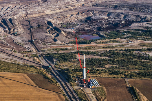 Aerial view of the lignite open cast mine Schleenhain with a large crane assembling a wind turbine tower section amidst the industrial landscape in Zwenkau Saxony Germany.