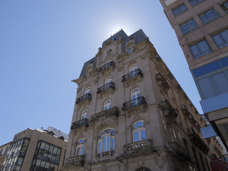 View of an ornate historic building with stone facade intricate balconies and arched windows under a clear blue sky in Vigo Pontevedra Spain.