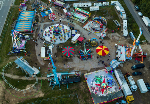Aerial view of a vibrant fairground with various amusement rides colorful tents and trailers set up in an open field in Vilnius Vilnius County Lithuania. Aerial view of a vibrant fairground with various amusement rides colorful tents and trailers set up in an open field in Vilnius Vilnius County Lithuania.